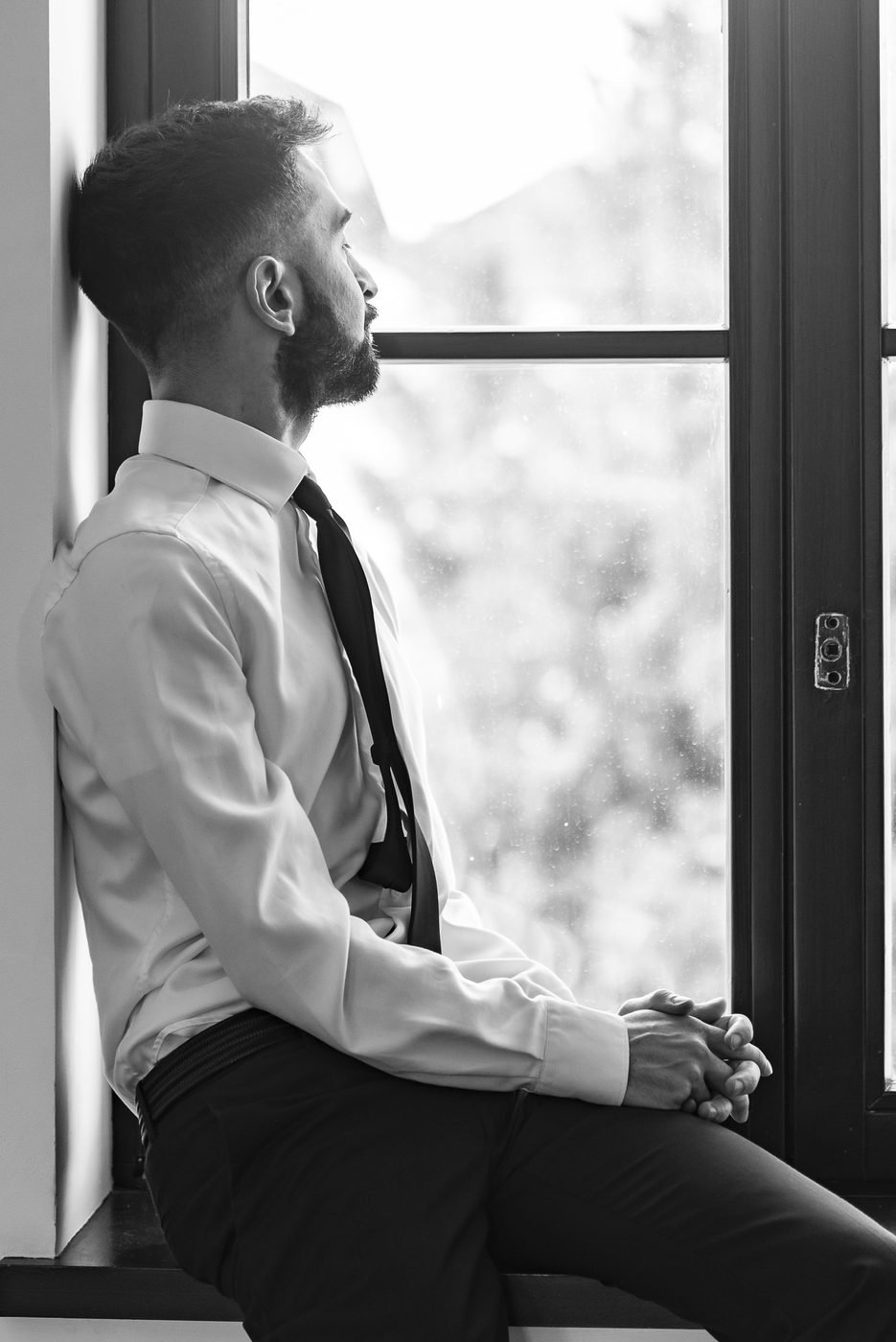 Jordan Nova en noir et blanc, assis à une fenêtre, le regard tourné vers l'extérieur
